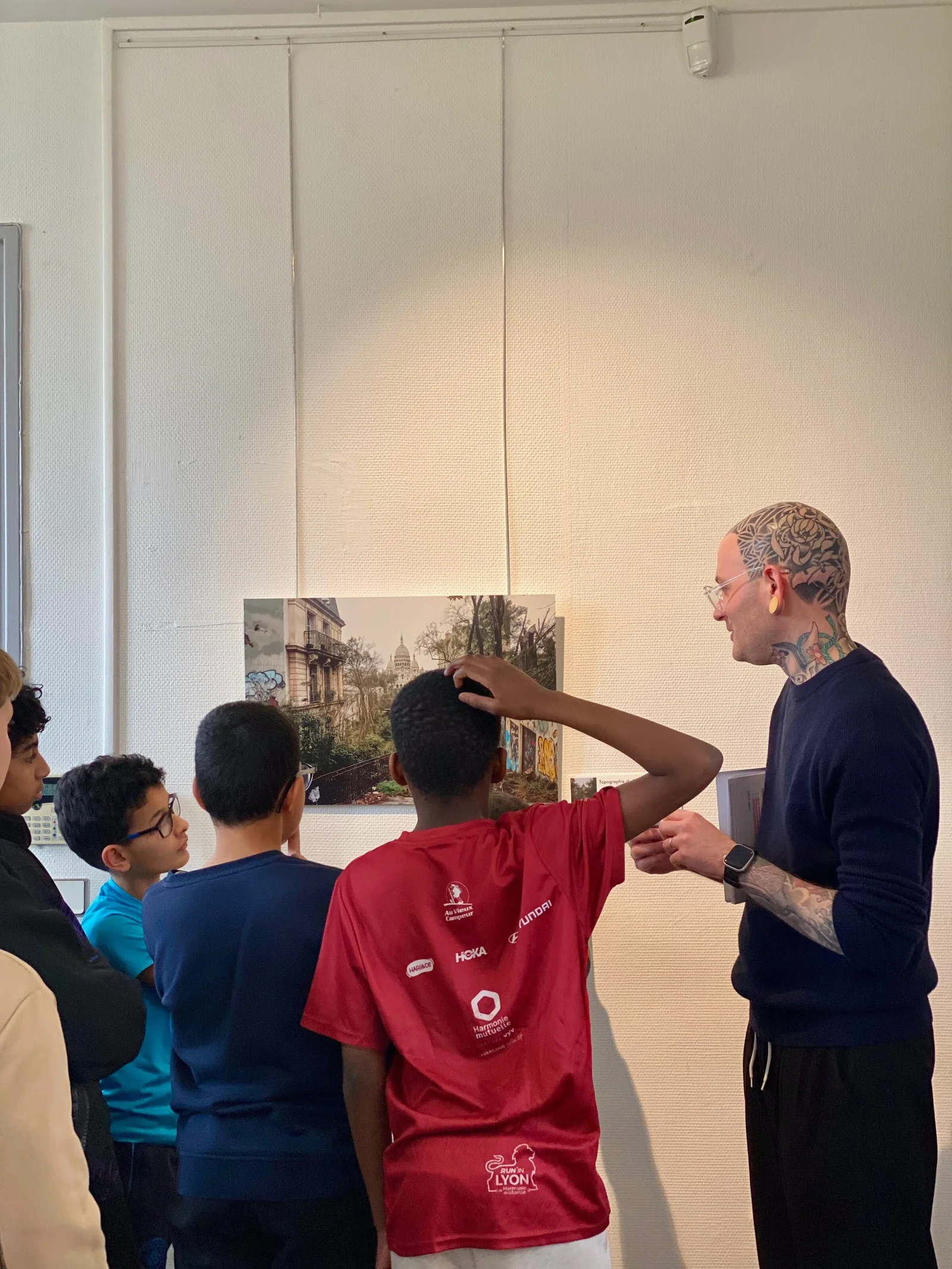 Le photographe devant l’œuvre Écho des Ruelles Silencieuses, un élève levant la main